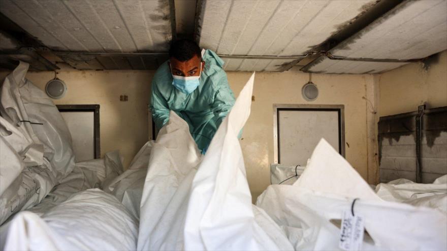 Un empleado del hospital revisa los restos de los palestinos liberados por Israel en virtud de un acuerdo de alto el fuego e intercambio de rehenes en Gaza, 18 de octubre de 2025. (Foto: AFP)