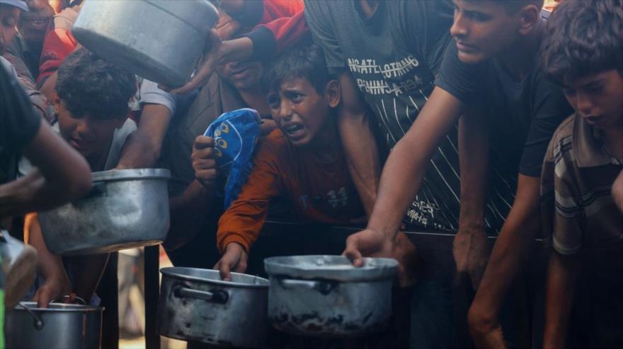 Palestinos desplazados esperan en largas filas para recibir una comida solidaria bajo tiendas de campaña abarrotadas en Jan Yunis mientras la escasez de alimentos se agrava debido al asedio, 21 de octubre de 2025. (Foto: AFP)