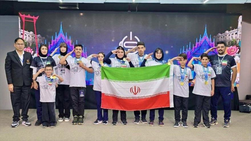 Equipo iraní de robótica sub-17 realiza un saludo militar ante la bandera nacional tras ganar campeonato asiático.