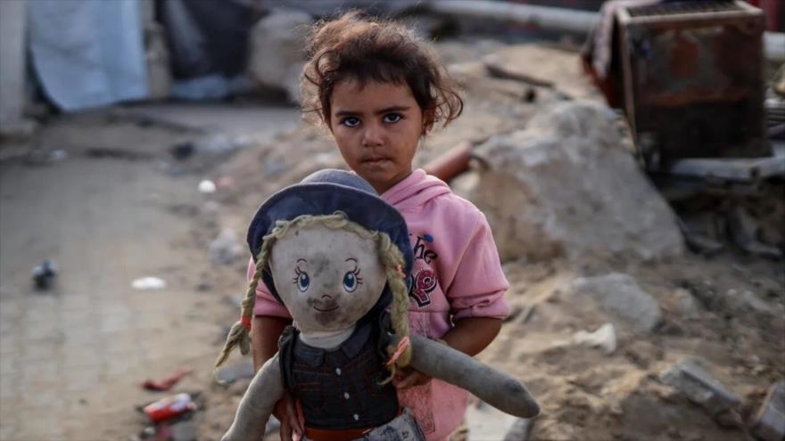 Una niña palestina lleva una muñeca entre sus manos. 