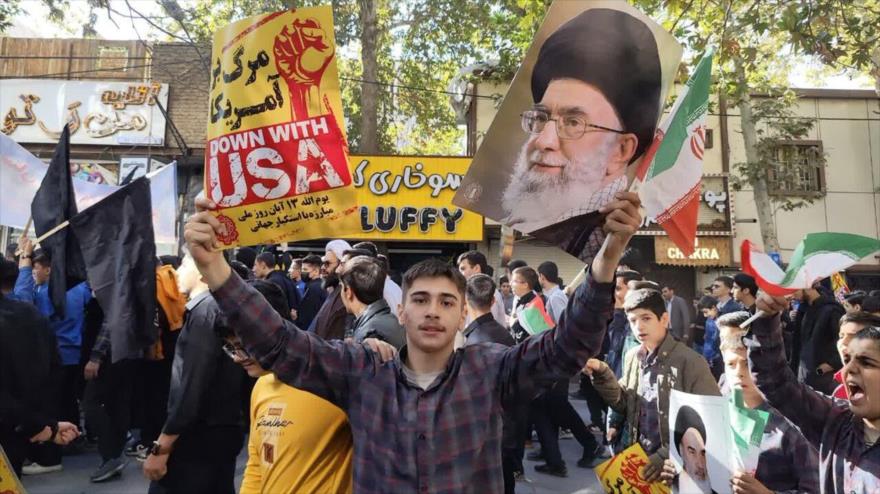 Jóvenes iraníes portan foto del Líder y pancartas en las que se lee eslóganes contra hegemonía de EEUU en las marchas del 13 de Aban, 4 de noviembre de 2025.