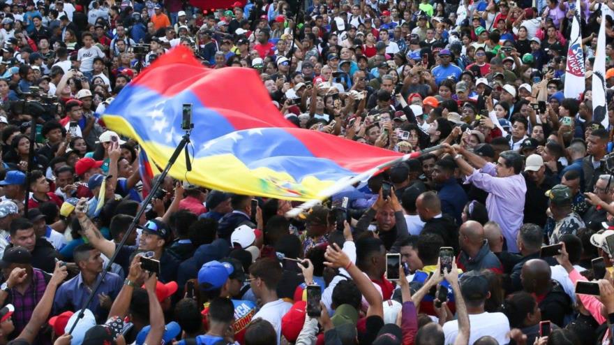 El presidente de Venezuela, Nicolás Maduro, ondea la bandera de Venezuela entre jóvenes de Venezuela en una marcha, 13 de noviembre de 2025.
