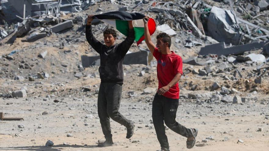 Dos gazatíes portan bandera de Palestina en Jan Yunis. (Foto: Reuters)