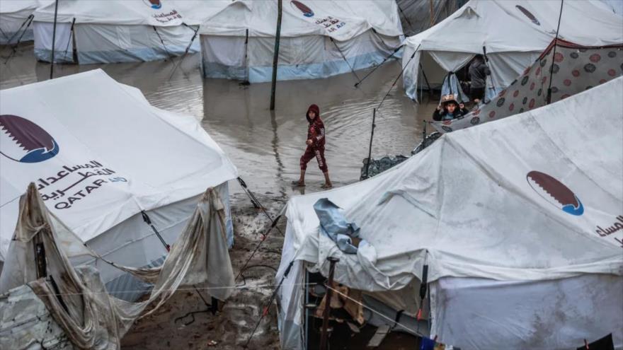 Un niño en un callejón inundado en un campamento de desplazados tras las fuertes lluvias en la ciudad de Gaza, 11 de diciembre de 2025. (Foto: AFP)