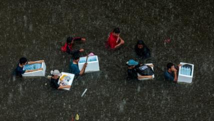 Residentes de Bangkok sortean aguas hasta la cintura por inundaciones